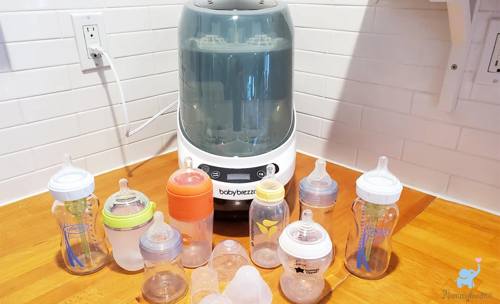 baby brezza bottle washer pro on counter with assorted baby bottles