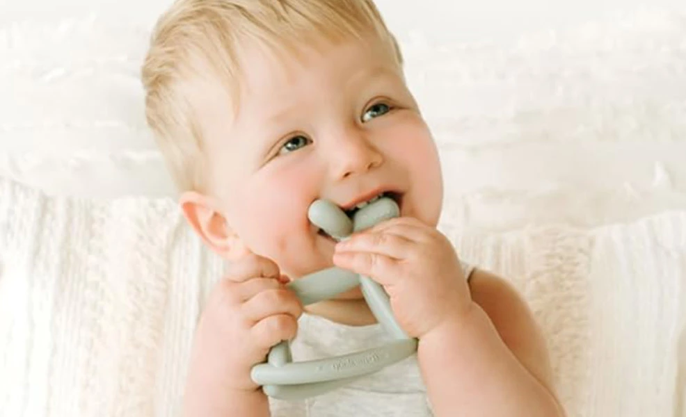 a baby chewing on a teething toy