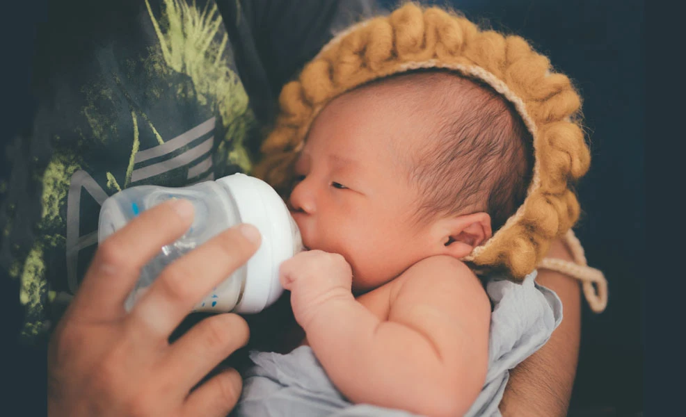 dad feeding baby drinking loulouka from a bottle