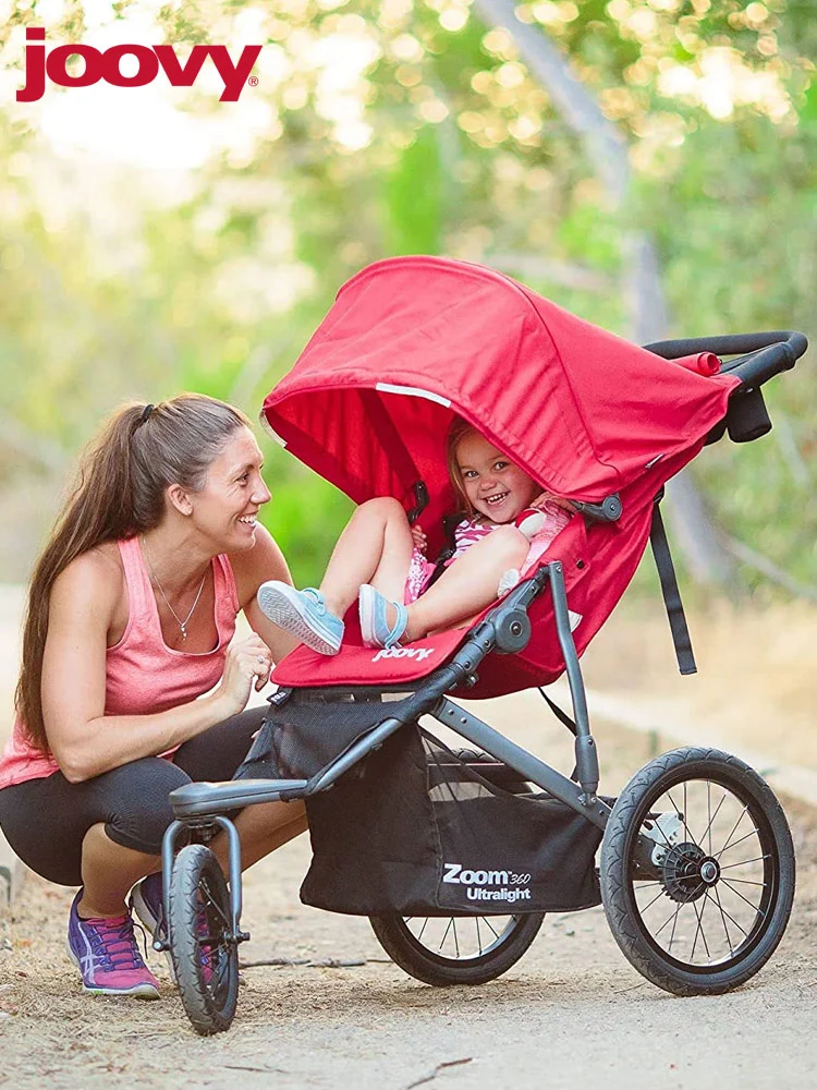 mother kneeling down and smiling with her toddler in the Joovy Zoom 360 stroller