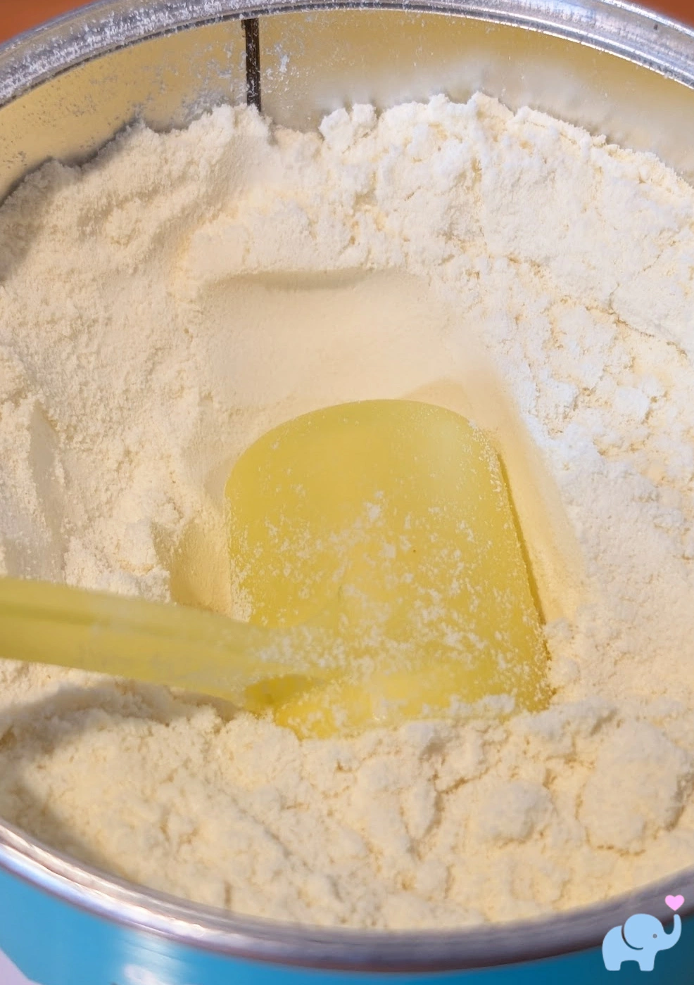 open can of Little Spoon formula showing the soft off-white powder and yellow scoop; each 8.5 gram scoop mixes with 2 ounces of water