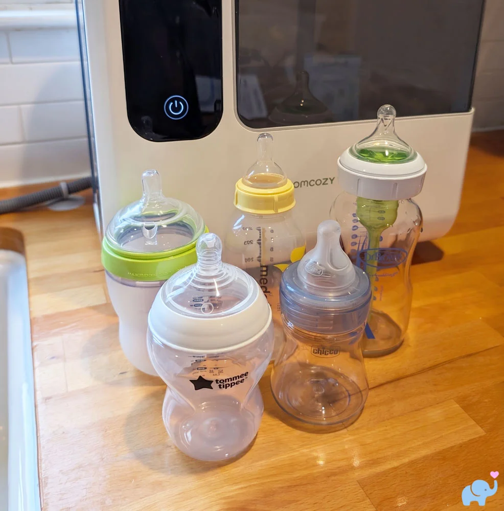 Five clean and dry baby bottles on the counter after washing in the Momcozy DeepClean Baby Bottle Washer D8
