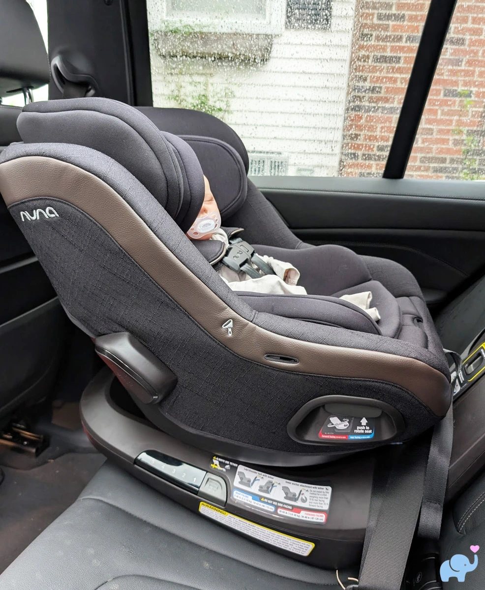 baby in nuna revv maxx rear-facing from another passenger perspective showing narrow base