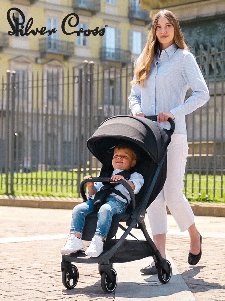 a mom pushing the silver cross clic storller with a toddler in the seat