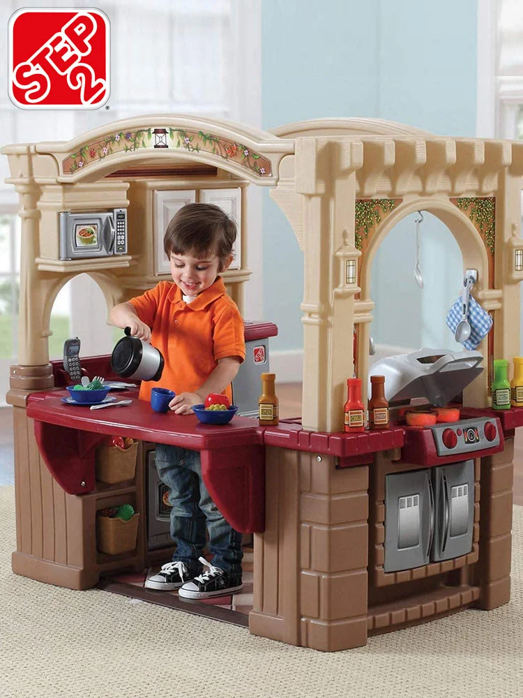 a boy preparing a pretend cup of coffee on the counter of the step2 grand walk-in play kitchen